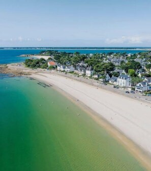 Eine Küstenlandschaft mit Sandstrand und einer Reihung von Häusern entlang der Uferlinie.