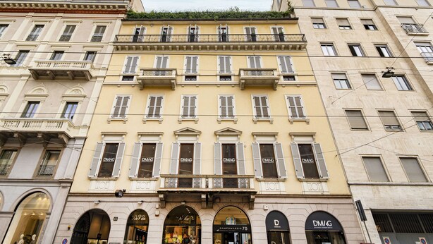 En byggnad med flera våningar i en klassisk arkitektonisk stil, med välvda fönster och balkonger.