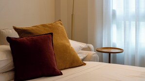 Ett hotellrum med en säng, två kuddar, ett runt bord och en golvlampa.