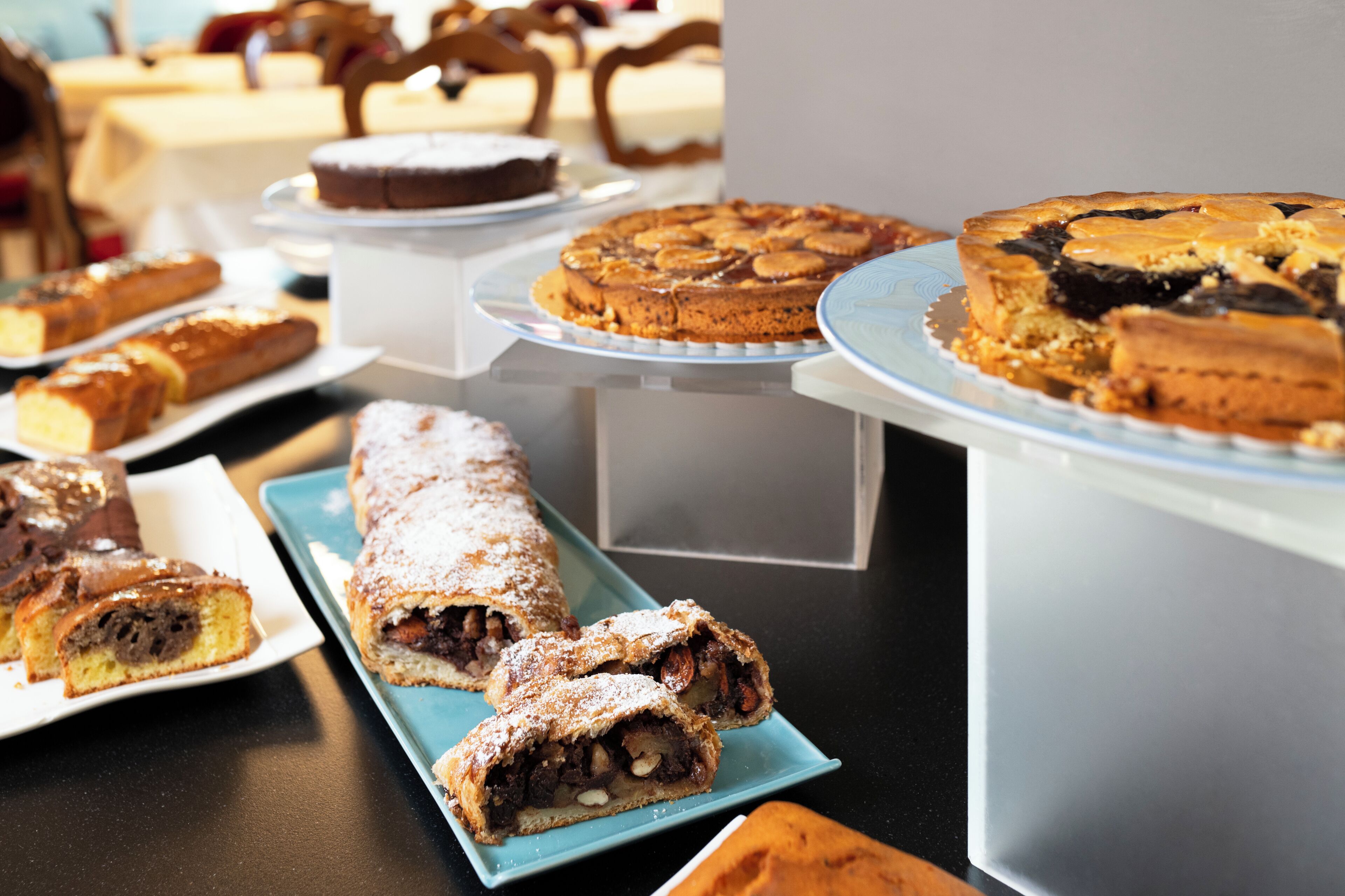 A variety of desserts on display, including cakes and pastries, arranged on serving trays and plates.
