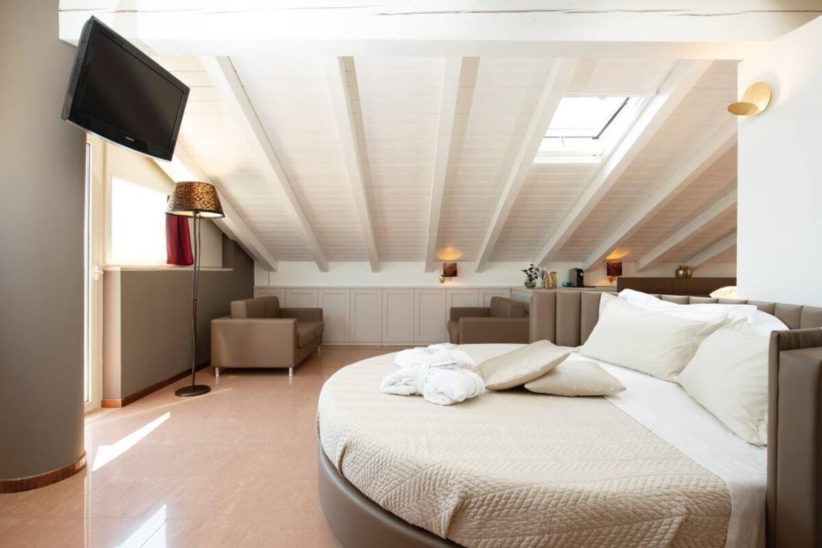 A bedroom with a bed, a TV, a desk, and a chair.
