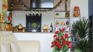 Een woonkamer met een bank, een bijzettafeltje en een vaas rode bloemen.