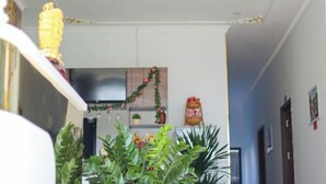 Een hal met een keuken op de achtergrond, met kastjes, een koelkast en een decoratieve guirlande.