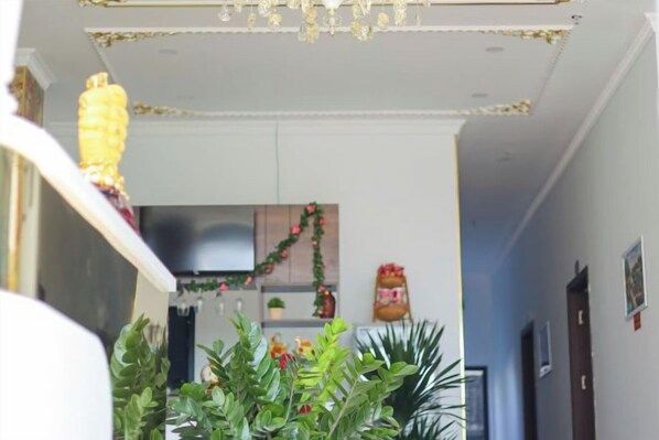 A hallway with a kitchen area in the background, featuring cabinets, a refrigerator, and a decorative garland. - Sea View Hotel Phan Thiet (Phan Thiet)