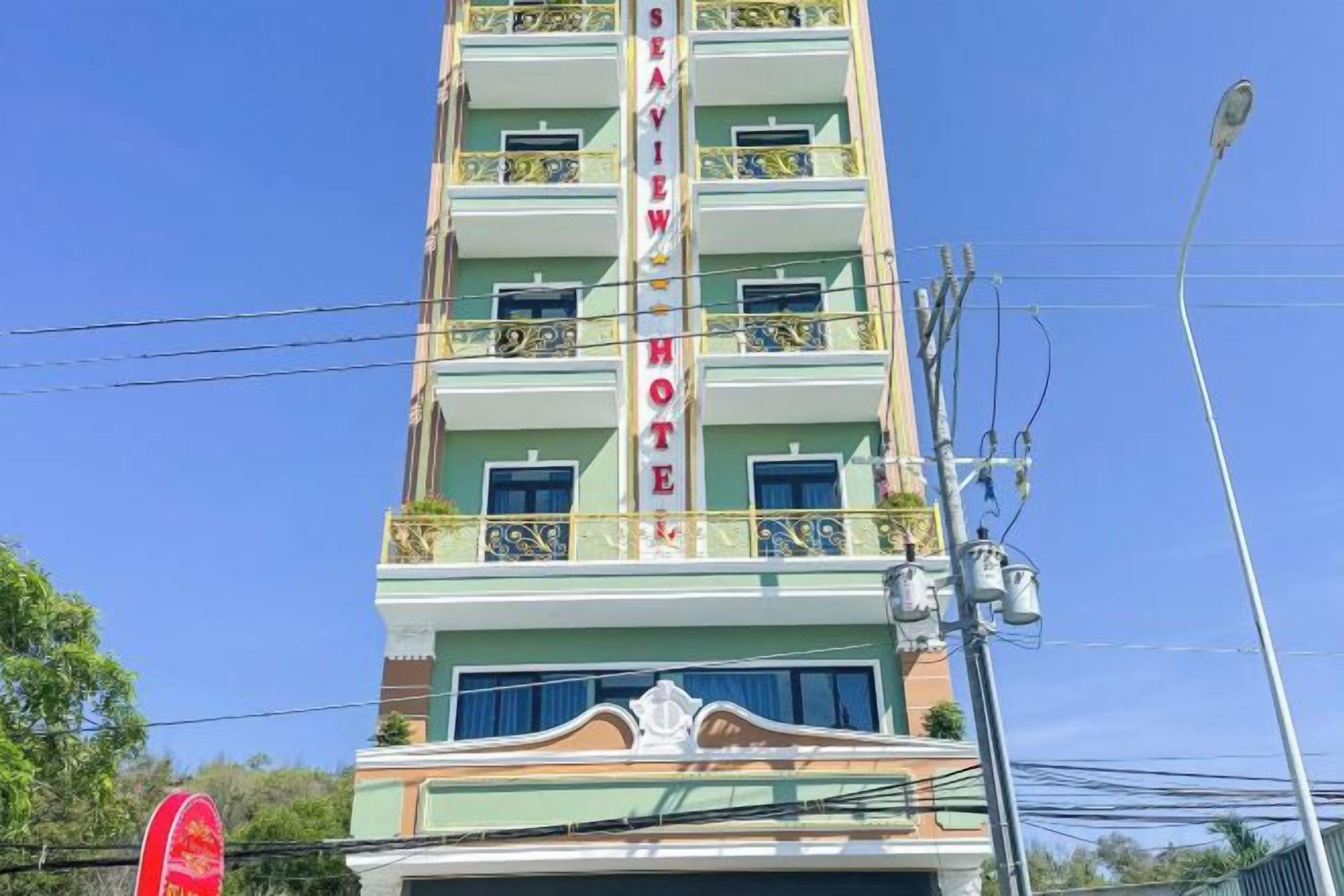 A multi-story hotel with balconies, a sign reading 'SEA VIEW HOTEL,' and a clear blue sky in the background.