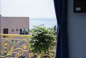 A balcony with yellow metal railings and a view of a building and the sea. - Sea View Hotel Phan Thiet (Phan Thiet)