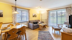 Een woonkamer met een bank, eettafel, stoelen, salontafel en een televisie.