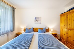 Un lit double avec une literie à carreaux, une tête de lit en bois, des lampes de chevet, un tableau au mur et une armoire en bois.