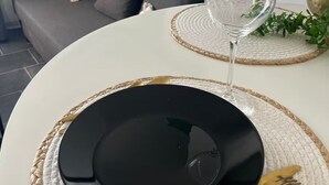 Une table à manger avec une assiette noire, un verre à vin et des couverts dorés.
