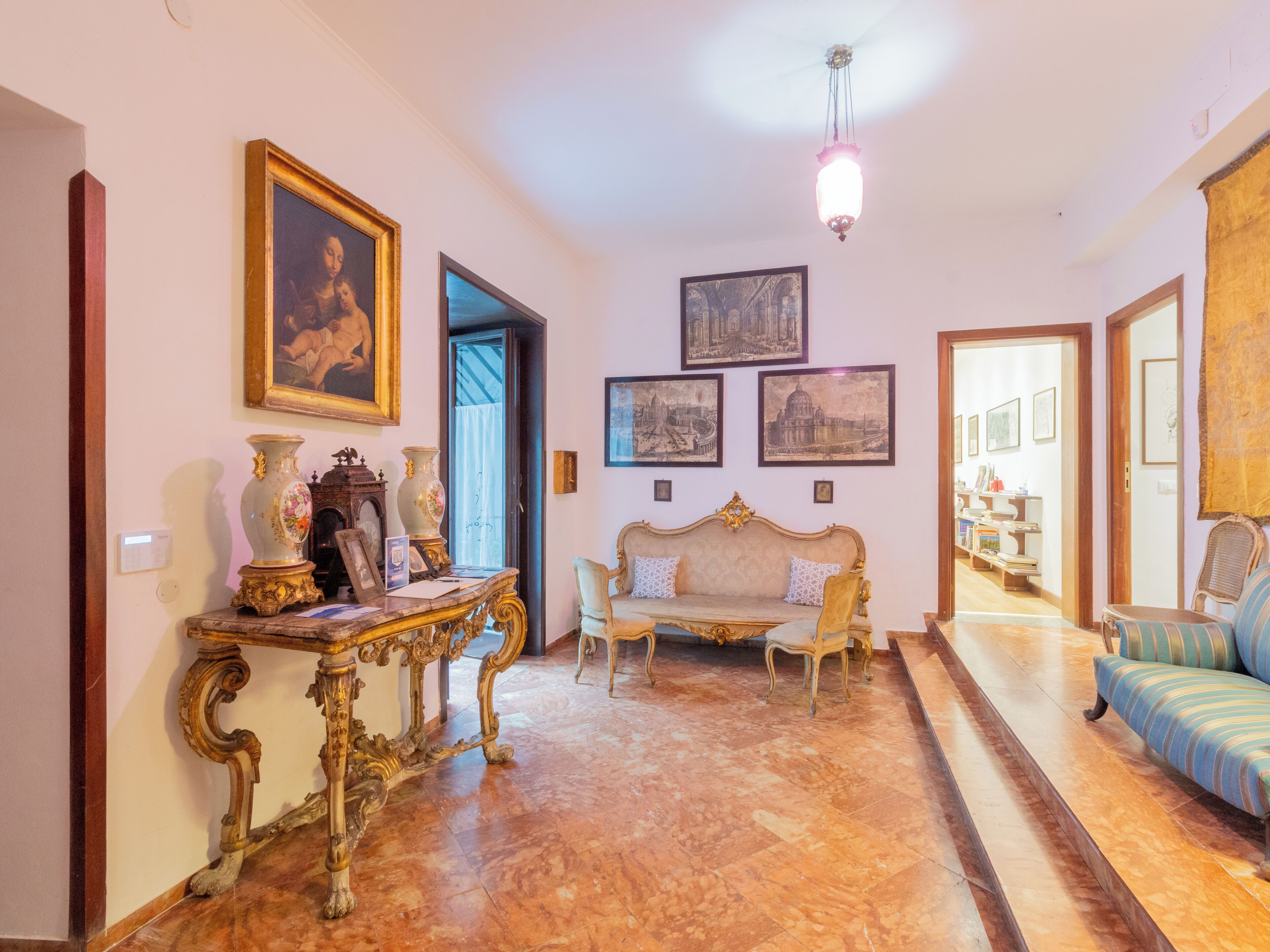 Un vaste hall d’entrée doté d’un sol en marbre, d’un canapé, d’une table agrémentée d’objets décoratifs et de tableaux encadrés accrochés aux murs.