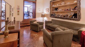 A living room with a sofa, armchairs, a table, and a mirror. - Palazzo del Bono suites (Palermo)