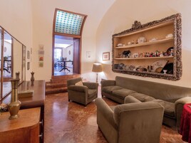 A living room with a sofa, armchairs, a table, and a mirror.