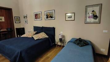 Een kamer met twee bedden, houten vloeren, een plafond met gedetailleerde decoraties en diverse ingelijste foto's aan de muur.