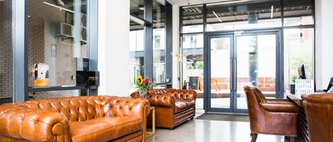 A modern lobby with leather sofas, a reception desk, and large glass doors leading outside.