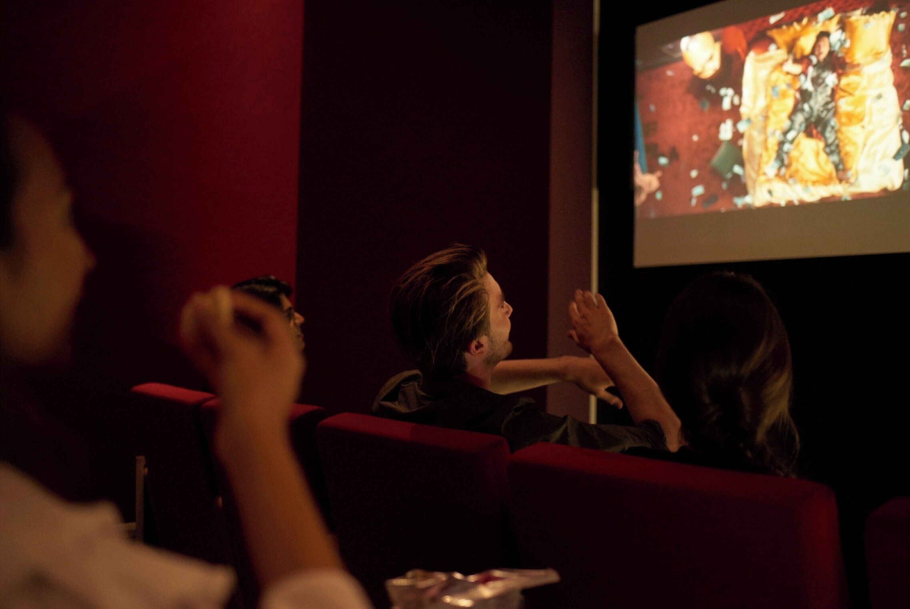 Cinema amb seients vermells i una pantalla que projecta una pel·lícula.