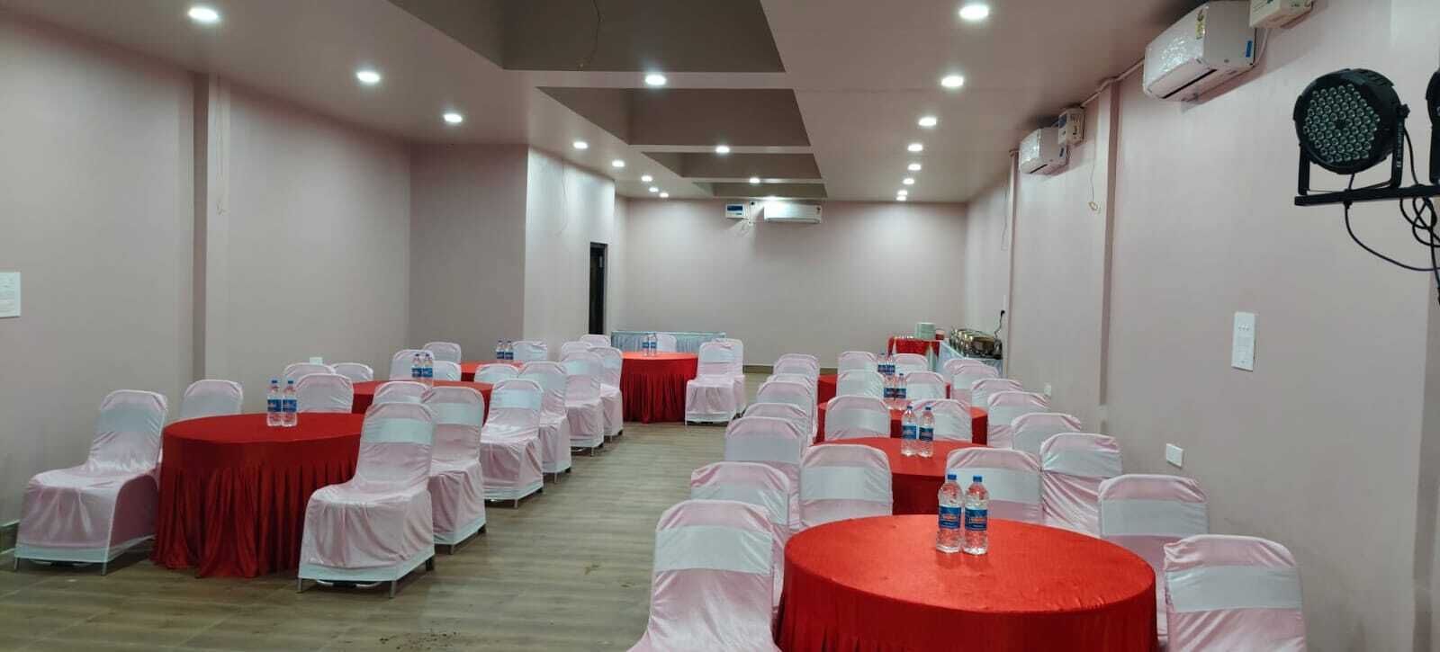 Un salón de conferencias con mesas redondas, sillas y botellas de agua.