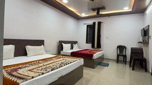 A modern hotel room with two beds, a ceiling fan, and a TV. - Hotel Moti Palace (Shri Madhopur)