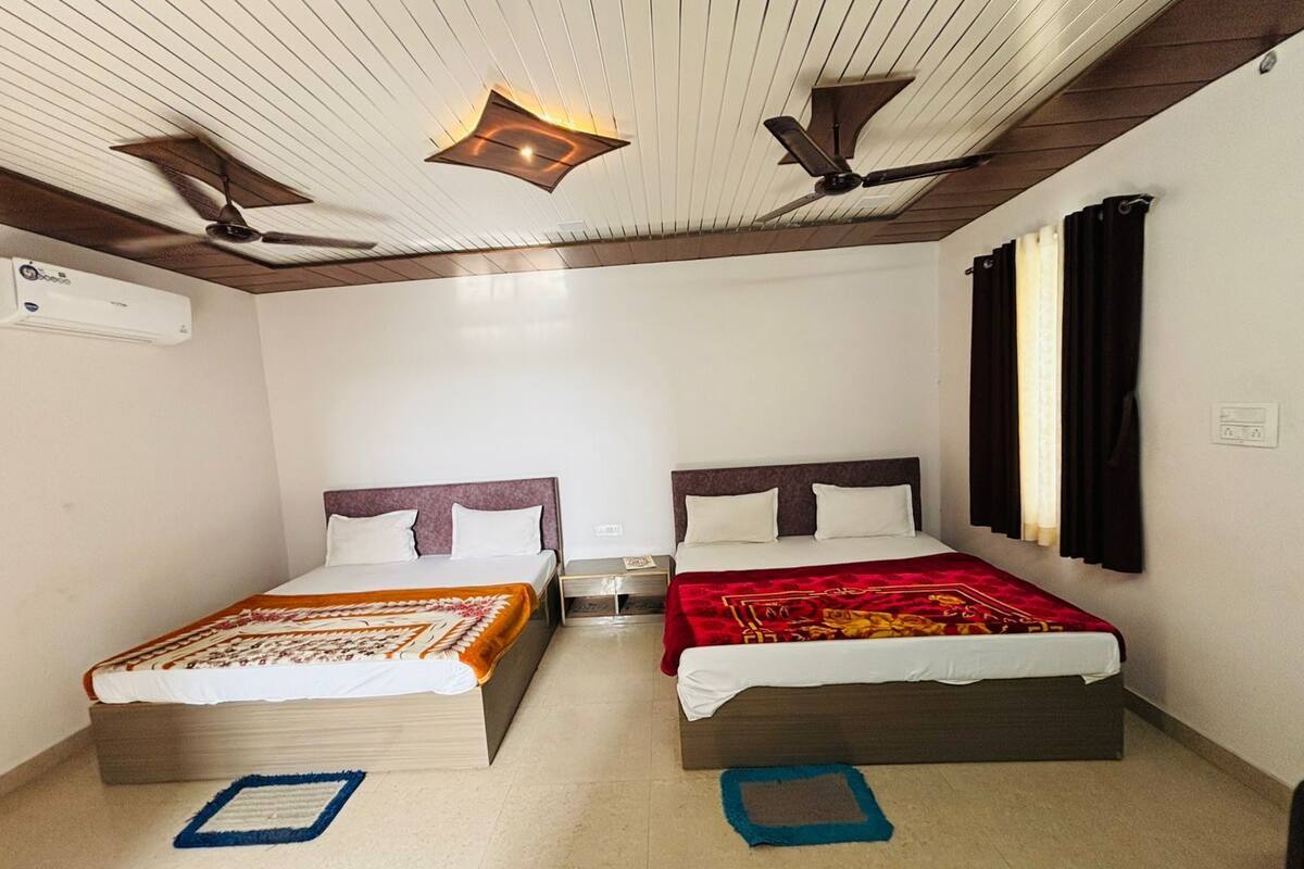 Ein Hotelzimmer mit zwei Betten, einem Deckenventilator, einer Klimaanlage und einem Fenster mit Vorhängen.