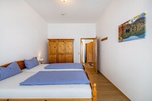A bedroom with two beds, wooden wardrobe, and a painting on the wall. - Apartment 'Fewo Brünnstein - Room 55' with Mountain View, Garden and Wi-Fi (Oberaudorf)