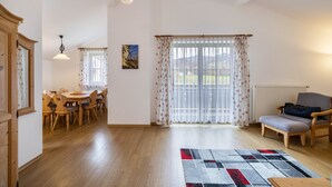 Een ruime kamer met een eethoek, een bank en uitzicht op het buiten.