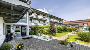 Een meerlaags gebouw met een overdekte ingang, terras en een verzorgde tuin.