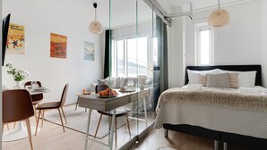 A modern hotel room with a bed, a desk, and a glass partition. - Topaasi - Nokia Arena by Come in (Tampere)