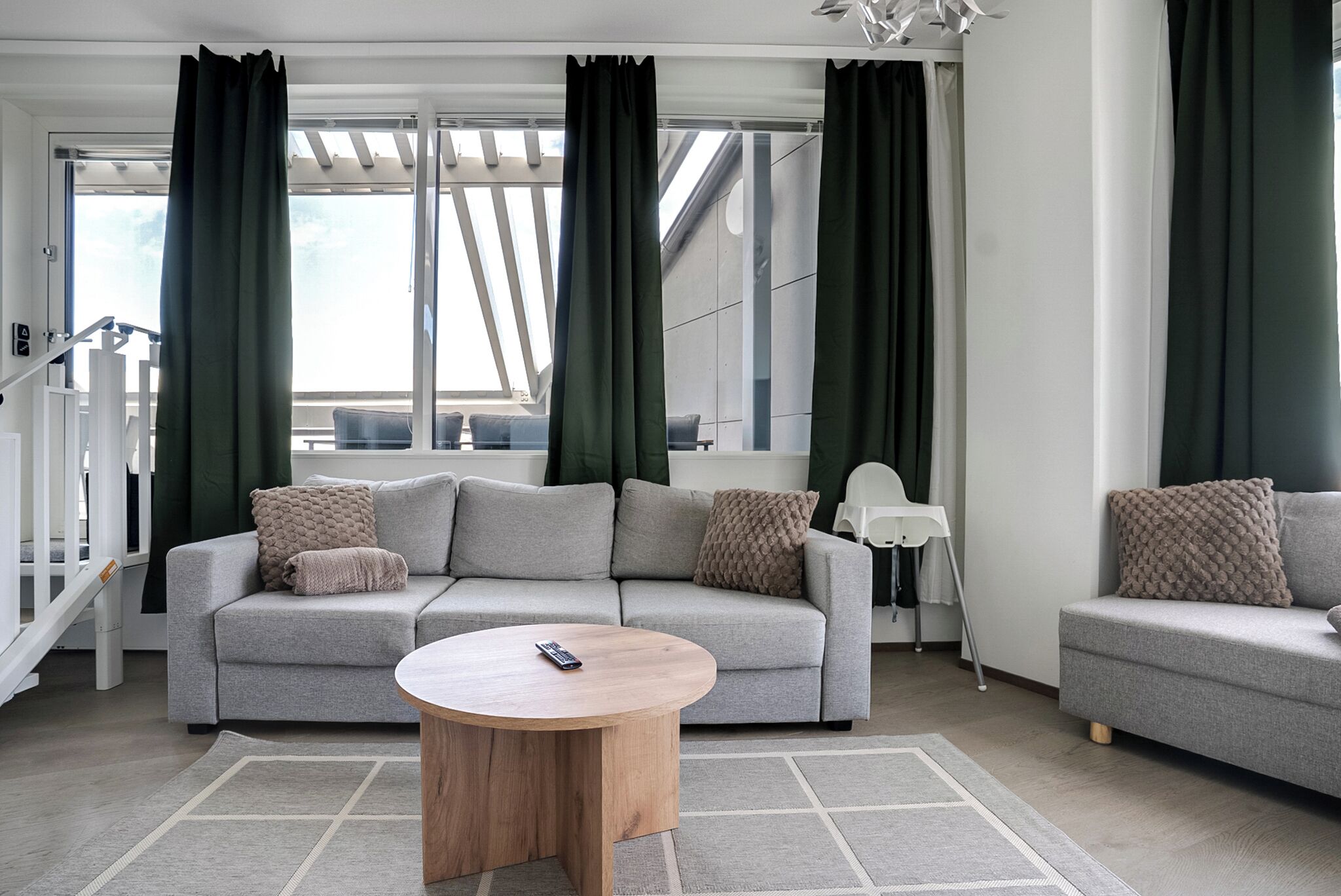 A modern living room with a grey sofa, a round wooden coffee table, and a white floor lamp.