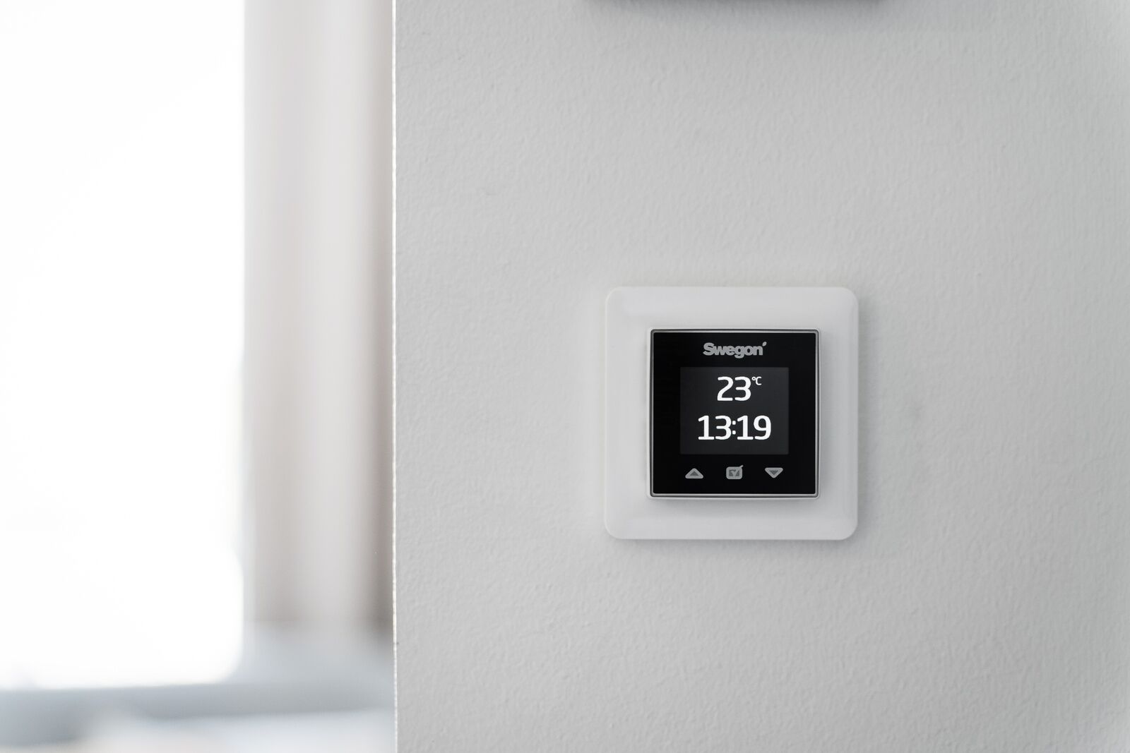 A Swigon thermostat displaying a temperature of 23°C and the time 13:19.