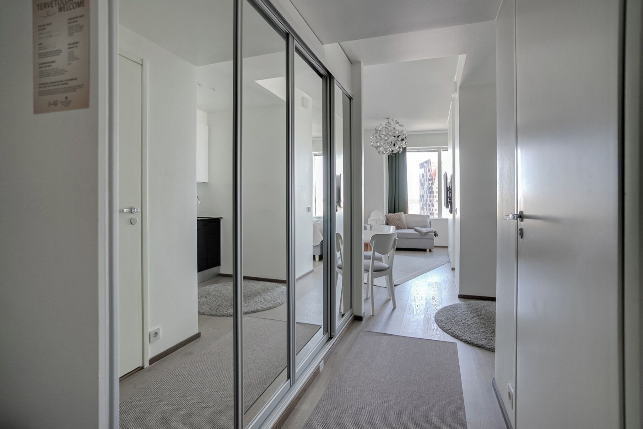 Ein moderner Hotelkorridor mit Schiebeglastüren, einer Couch und einem Kronleuchter.