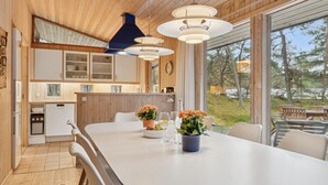 Moderni keittiö, jossa on puiset kaapit, suuri keittiösaareke istuimineen ja suuret ikkunat, joista avautuu näkymä ulos.