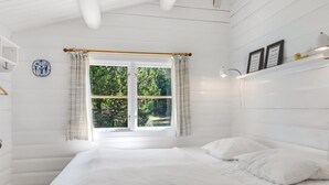 Ein Schlafzimmer mit großem Fenster, einem Bett, einem Nachttisch und einer Wandregal mit Dekoration.