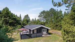 Eine kleine Holzhütte mit einer Terrasse, umgeben von Bäumen.