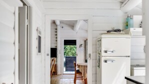 Eine schmale Küche mit Holzboden, einem weißen Kühlschrank und einem Essbereich mit Tisch und Stühlen.