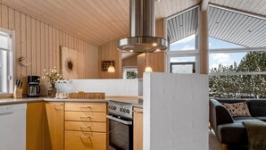 Une cuisine moderne avec des meubles en bois, une cuisinière encastrée et une grande fenêtre donnant sur un jardin.