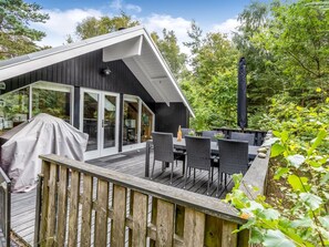 Eine moderne Terrassenanlage im Freien mit Essbereich, überdachtem Grill und großem Sonnenschirm.