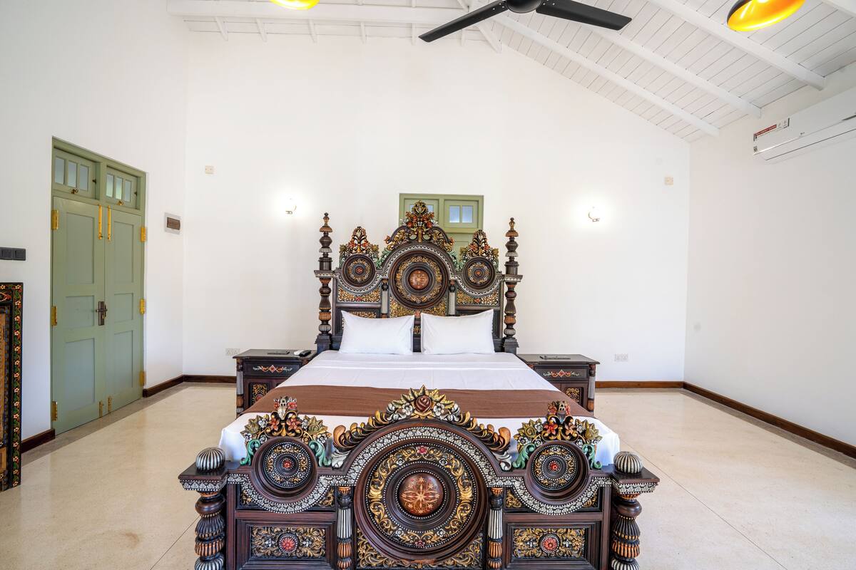 Una habitación amplia con una cama grande, una puerta verde y un ventilador de techo.