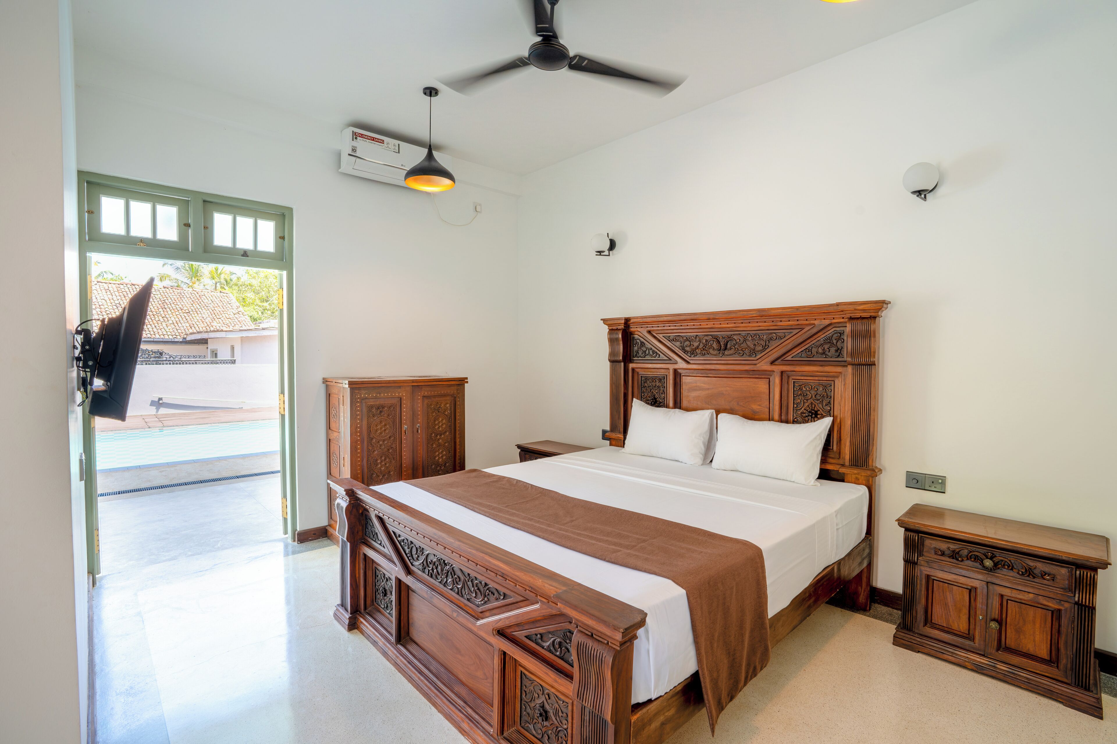 Une chambre à coucher avec un lit en bois, un ventilateur de plafond et une table de chevet.