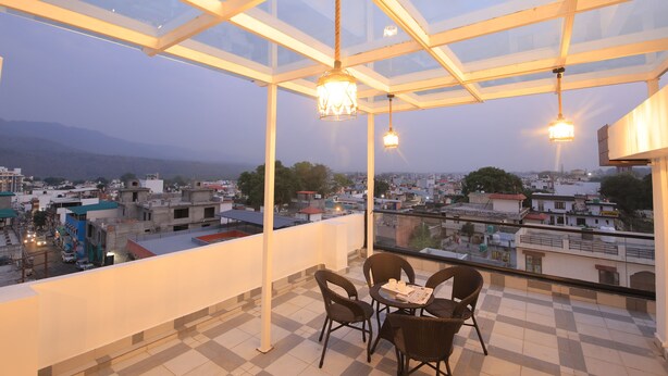 Ein Balkon mit Glasdach, Korbstühlen und einem Tisch.
