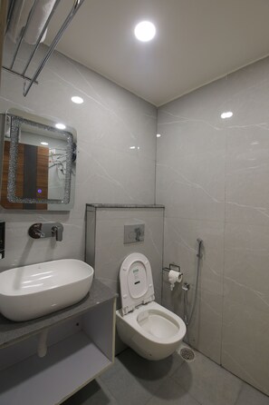 A modern bathroom with a white sink, toilet, and shower. - Ganga Inn By YatriMap (Rishikesh)