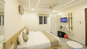 Ein modernes Hotelzimmer mit Bett, kleinem Tisch, Fernseher und Kleiderschrank.