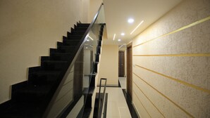 Ein modernes Interieur mit einer schwarzen Treppe, einer Glastrennwand und einer Wand mit strukturierter Oberfläche und gelben Linien.