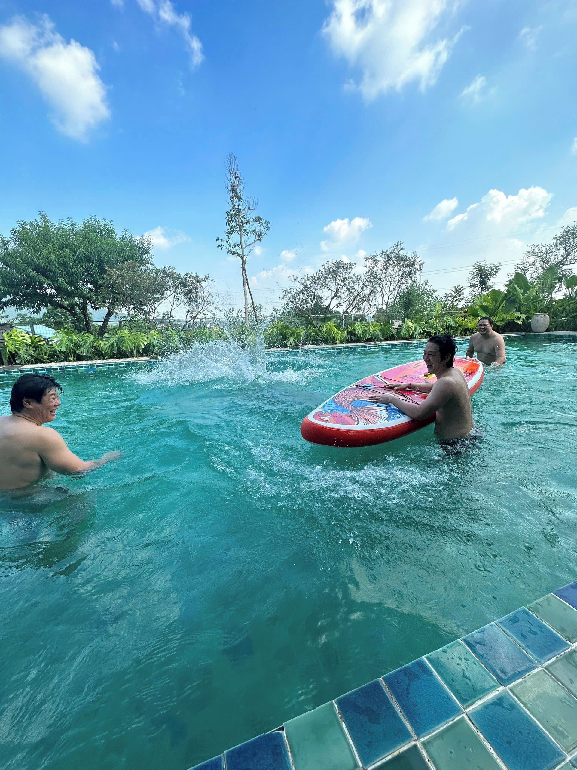 Une piscine à l’eau d’un bleu cristallin, entourée d’une végétation luxuriante et d’arbres.