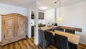 A modern kitchen with a wooden dining table, black chairs, a pendant light, and a built-in oven. - Apartment 'Fewo Brünnstein - Zimmer 50' with Mountain View, Shared Garden & Wi-Fi (Oberaudorf)