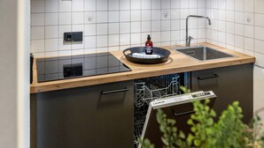 A modern kitchen with a wooden countertop, a built-in dishwasher, and a sink. - Apartment 'Fewo Brünnstein - Zimmer 50' with Mountain View, Shared Garden & Wi-Fi (Oberaudorf)