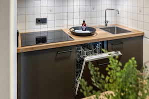 A modern kitchen with a wooden countertop, a built-in dishwasher, and a sink. - Apartment 'Fewo Brünnstein - Zimmer 50' with Mountain View, Shared Garden & Wi-Fi (Oberaudorf)