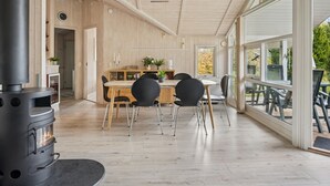 Un interno moderno con zona pranzo, un'ampia finestra e un camino a legna.