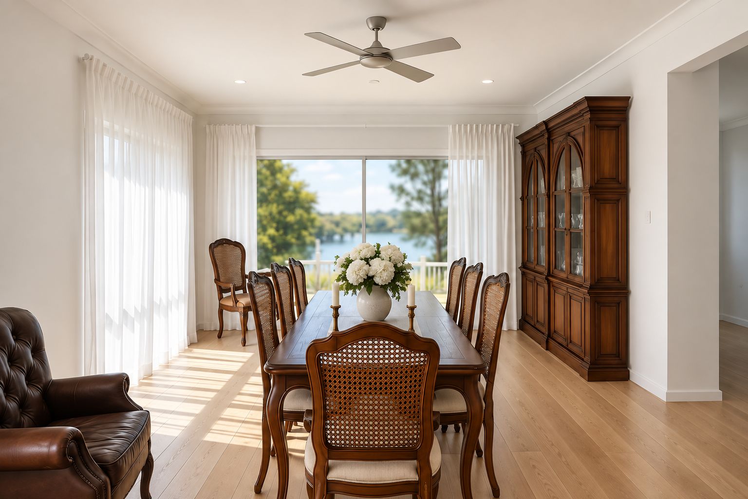 A dining room with a large wooden table, chairs, a cabinet, and a ceiling fan.