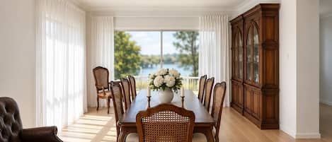 Une salle à manger avec une grande table en bois, des chaises, un buffet et un ventilateur de plafond.
