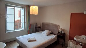 Un dormitorio con cama, mesita de noche, lámpara y ventana con cortinas.