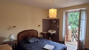 Un dormitorio con cama, mesita de noche, lámpara y ventana con vistas al exterior.